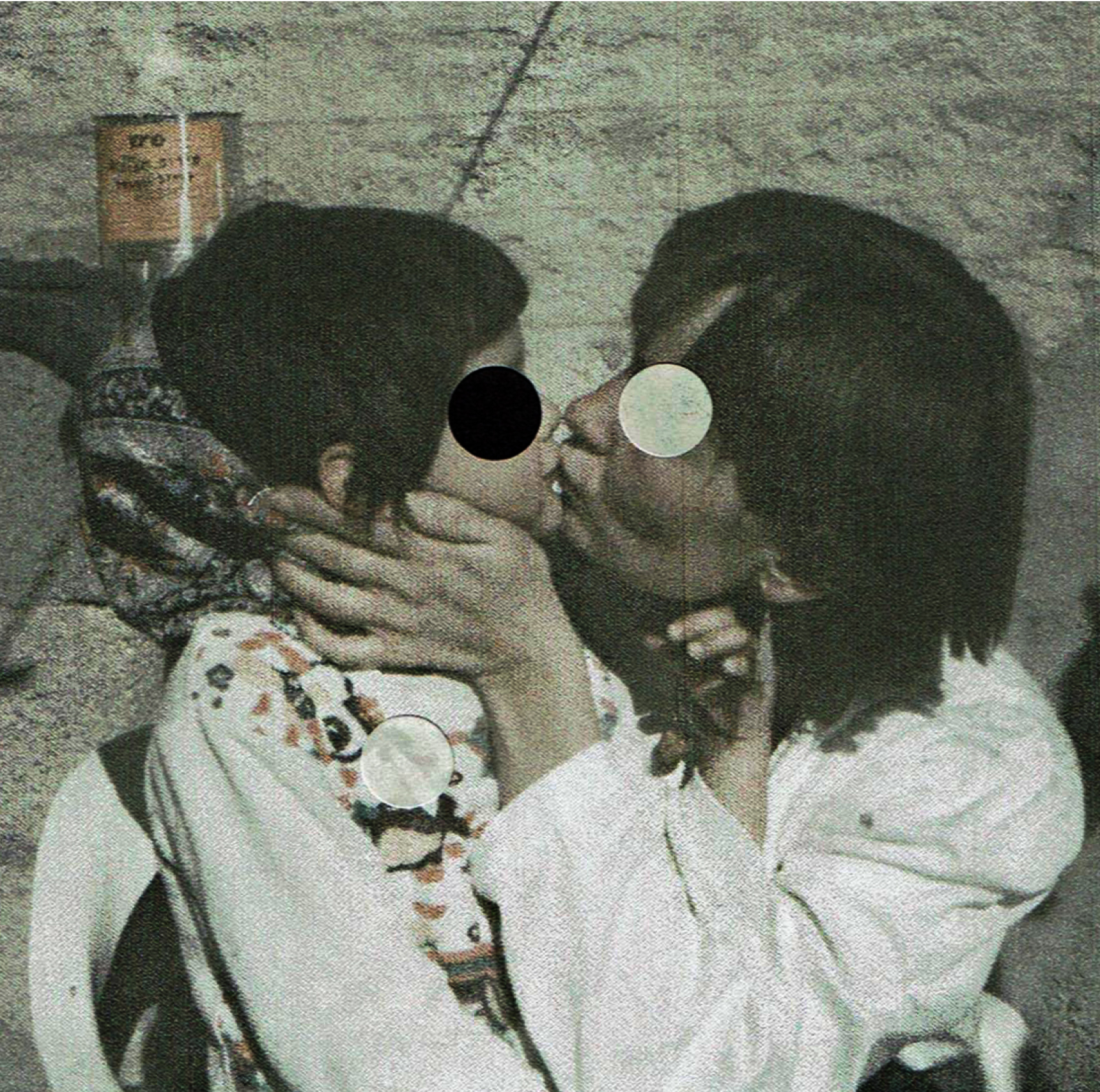 parent kisses a child. Black and white paper circles hide their faces.